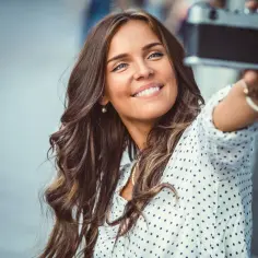 Uśmiechnięta brunetka robi sobie selfie starą kamerą.