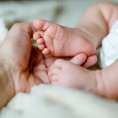 Delikatne stópki dziecka w dłoni rodzica. Każdy dzień to nowy etap, jak w kalendarzu skoków rozwojowych.